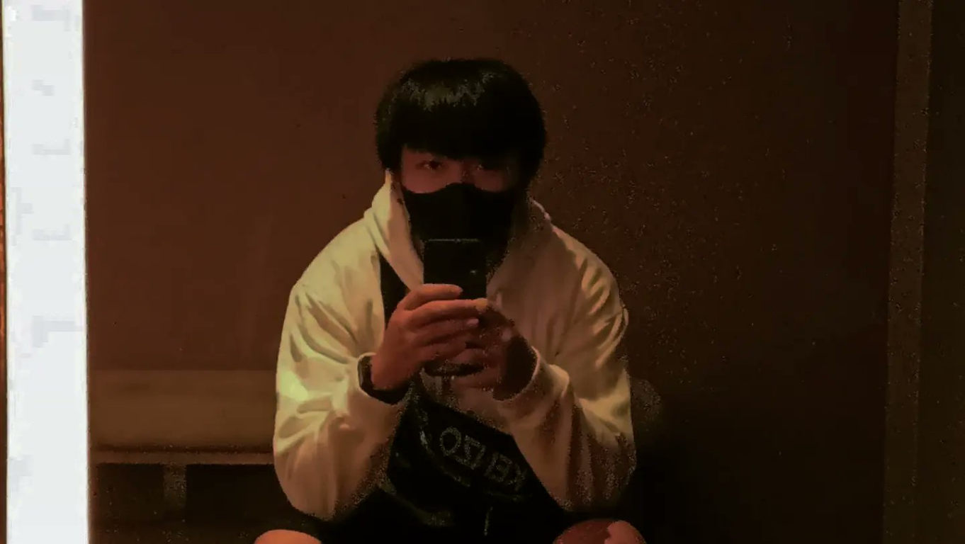 Yavin wearing a light-colored hoodie and black face mask